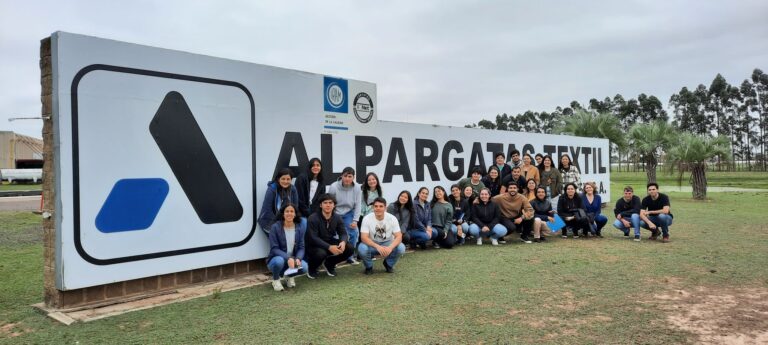 Grupo de estudiantes frente al cartel de Alpargatas Textil